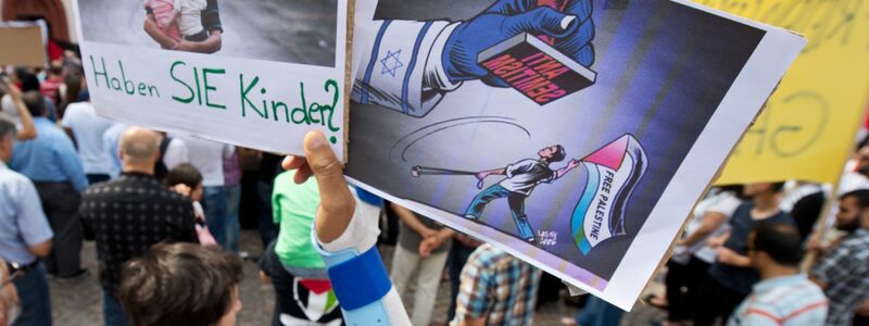 Ein Junge hält ein Plakat hoch, auf dem ein propalästinensischer Demonstrant unter einem Stempel mit der Aufschrift  Anti Semitismus steht. - Foto: picture alliance / dpa