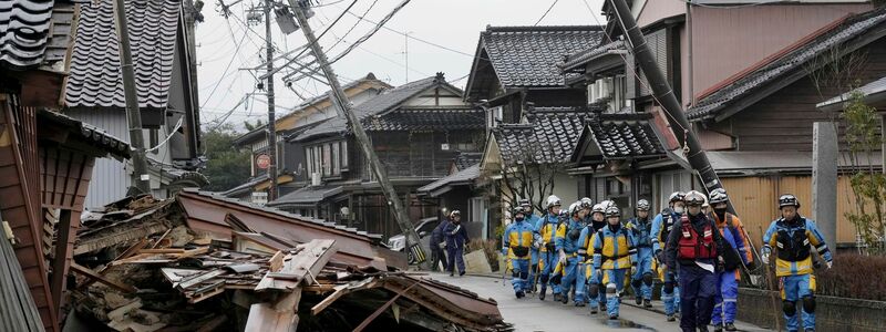 Polizisten gehen an eingestürzten Häusern vorbei, die von den Erdbeben in Suzu, Präfektur Ishikawa getroffen wurden. - Foto: Uncredited/Kyodo News/AP/dpa