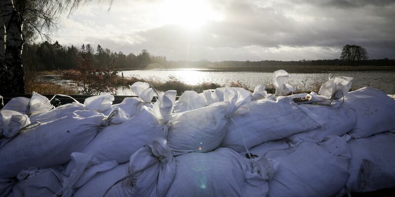 Sandsäcke an einer Landstraße am Ortseingang von Sandkrug bei Oldenburg. - Foto: Christian Charisius/dpa
