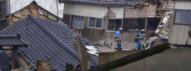 Einsatzkräfte der Polizei durchsuchen nach dem Erdbeben beschädigte Häuser in Wajima. - Foto: Uncredited/Kyodo News/AP
