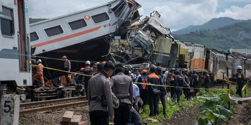 Rettungskräfte inspizieren die Zugwracks nach dem Zusammenstoß: In beiden Zügen waren insgesamt 478 Menschen unterwegs. - Foto: Abdan Syakura/AP/dpa