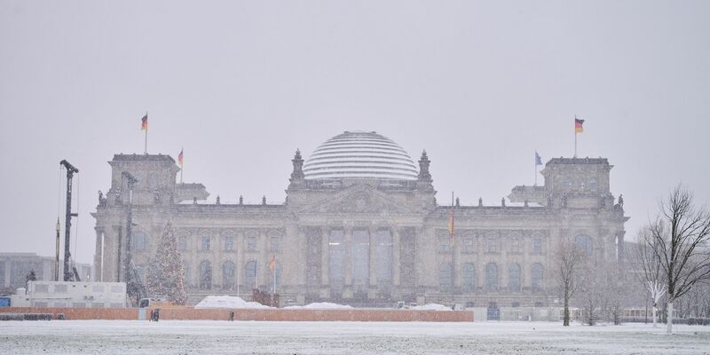 Das Reichstagsgebäude ist mit Schnee bedeckt. - Foto: Annette Riedl/dpa