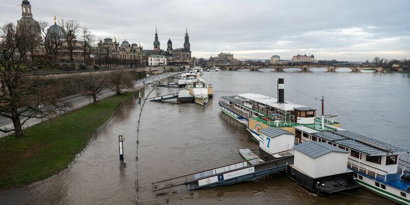 Ein Mann fährt mit seinem Fahrrad über die vom Hochwasser überfluteten Elbwiesen am Königsufer in Dresden. - Foto: Robert Michael/dpa