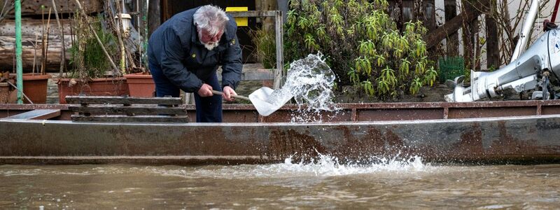 Ein Anwohner an der Fischerei in Bamberg schöpft Wasser aus einem Boot. - Foto: Pia Bayer/dpa