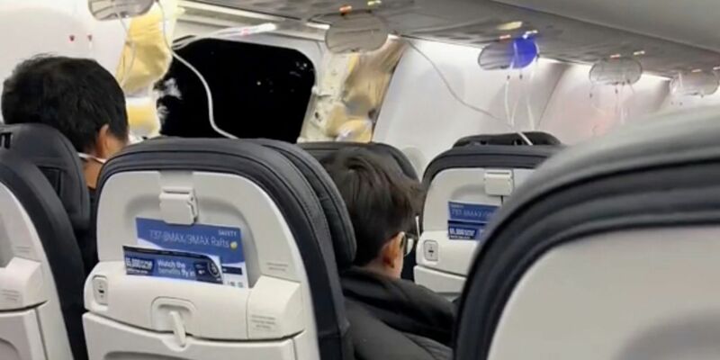 Passagiere sitzen in einer Boeing 737-9 Max in der Nähe des abgerissenen Kabinenteils. - Foto: Elizabeth Le/Elizabeth Le/AP