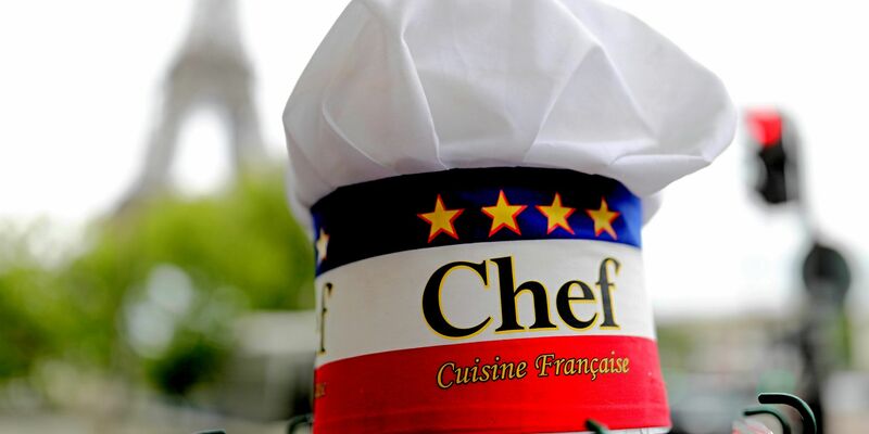 Eine Kochmütze wird an einem Souvenirstand beim Eiffelturm angeboten. In Frankreichs Gastronomie werden viele Stellen von Ausländern besetzt. - Foto: Michael Kappeler/dpa