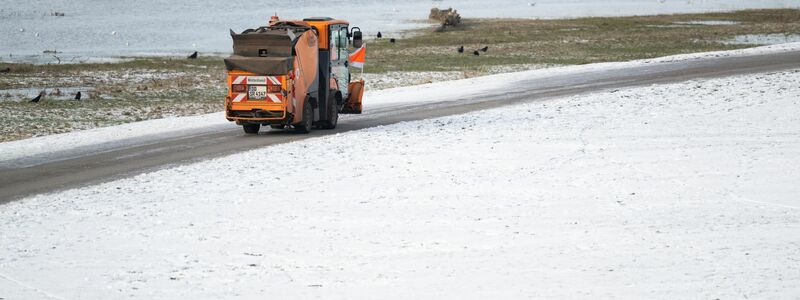 Ein Winterdienst-Fahrzeug fährt am Vormittag an den verschneiten Elbwiesen auf dem Radweg in Dresden entlang. - Foto: Robert Michael/dpa