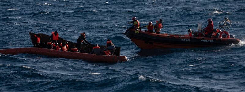 Migranten sitzen in einem Boot im Mittelmeer; Rettungskräfte versuchen, ihnen zu helfen. - Foto: Antonio Sempere/EUROPA PRESS/dpa