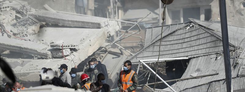 Rettungskräfte stehen in Damaskus an dem durch den Luftangriff zerstörten Gebäude. - Foto: Omar Sanadiki/AP/dpa