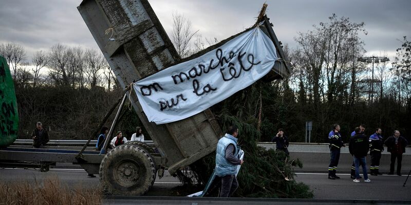 Landwirte kippen Zweige und Äste auf die Fahrbahn, während sie eine Autobahn in der Nähe von Lyon blockieren. - Foto: Laurent Cipriani/AP/dpa