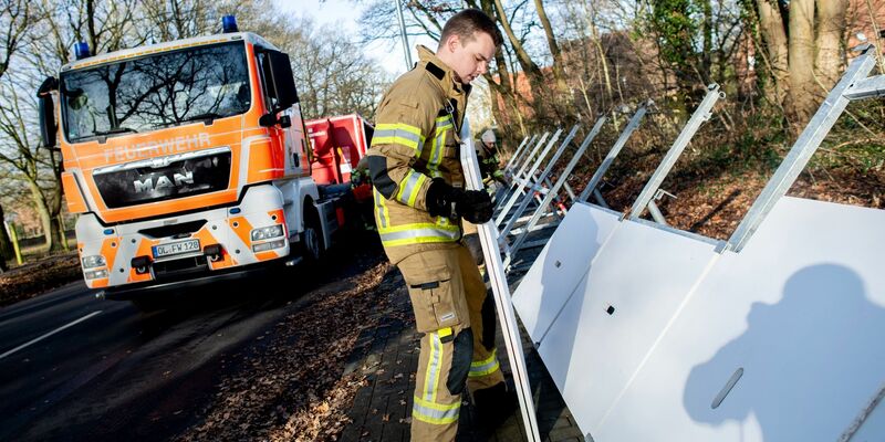Einsatzkräfte der Feuerwehr bauen ein mobiles Deichsystem ab. - Foto: Hauke-Christian Dittrich/dpa