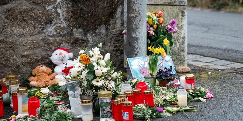 An einer Mauer vor dem Kinder- und Jugendheim in Wunsiedel, in dem eine Zehnjährige tot aufgefunden wurde, liegen Blumen, Kerzen und Stofftiere. - Foto: Daniel Vogl/dpa