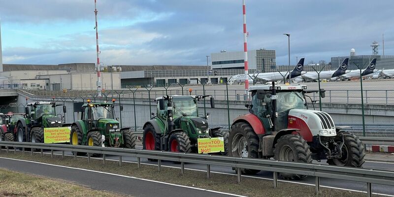 Traktoren fahren auf einer Straße am Flughafen Frankfurt vorbei. Wie ein Polizeisprecher sagte, begaben sich die Bauern am Morgen gegen 6 Uhr Richtung Airport. Geplant sei eine Protestfahrt rund um das Gelände. - Foto: Mike Seeboth/dpa