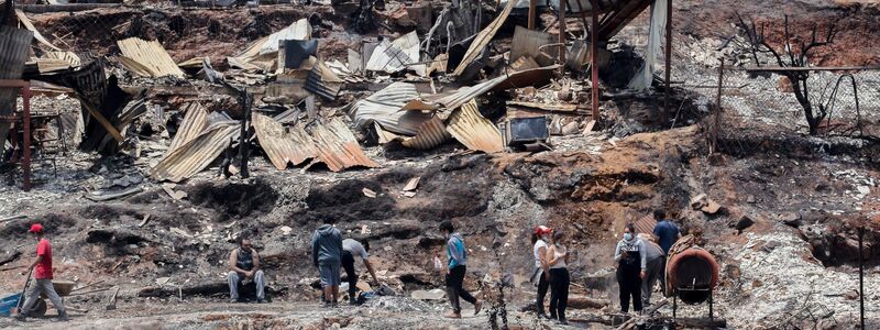 Einheimische arbeiten zwischen den Trümmern von ausgebrannten Häusern. - Foto: Cristobal Basaure/AP