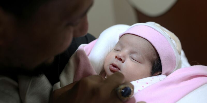 Adoptivvater Chalil Sawadi betrachtet Afraa wenige Tage nach ihrer Geburt. Das kleine Mädchen wurde unter Trümmern des Erdbebens in Syrien am 6. Februar 2023 geboren. - Foto: Ghaith Alsayed/AP/dpa