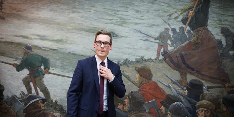 Thorben Schütt im Kreistagssaal von Heide vor dem Ölbild «Die Schlacht bei Hemmingstedt - anno 1500» (Max Friedrich Koch - 1859-1930). - Foto: Christian Charisius/dpa