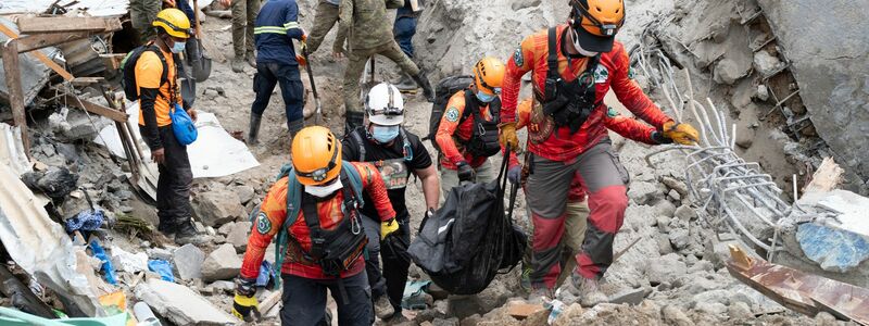 Rettungskräfte tragen ein Opfer aus dem von einem Erdrutsch betroffenen Dorf Masara. - Foto: Uncredited/AP/dpa