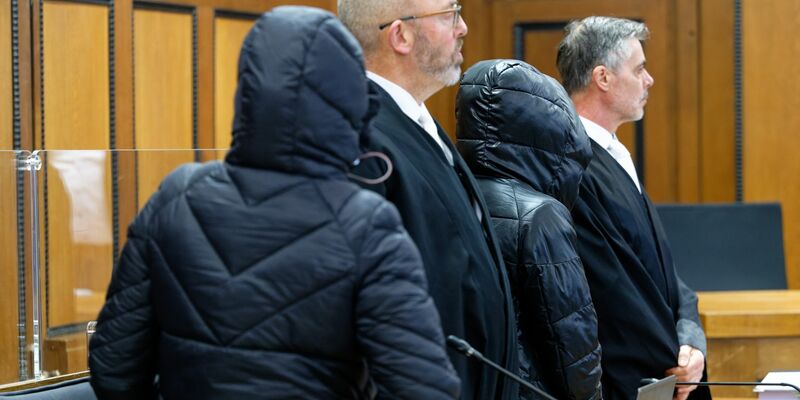 Die beiden Angeklagten und die Rechtsanwälte vor Beginn der Verhandlung im Gerichtssaal. - Foto: Henning Kaiser/dpa