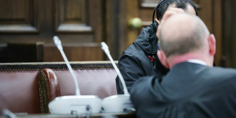 Einer der beiden Angeklagten (verdeckt) spricht mit seinem Anwalt Hannes Linke vor Prozessbeginn im Gerichtssaal des Strafjustizgebäudes. - Foto: Christian Charisius/dpa-Pool/dpa