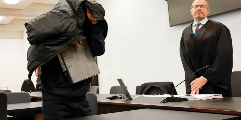 Der ehemalige Security-Mann bedeckt im Gerichtsaal seinen Kopf mit einer Jacke. - Foto: Daniel Löb/dpa