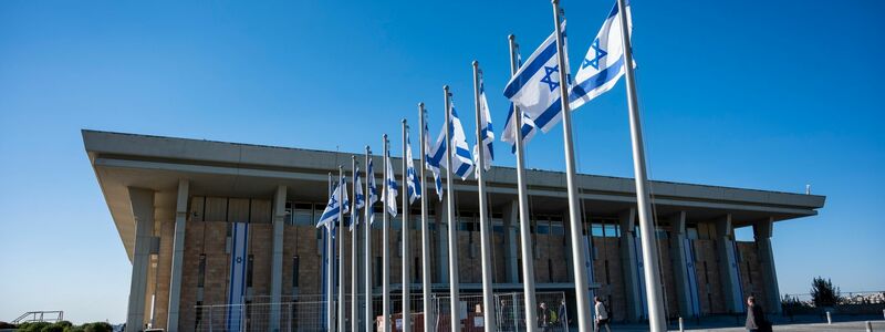 Israelische Flaggen wehen vor dem Parlamentsgebäude in Jerusalem. - Foto: Christophe Gateau/dpa