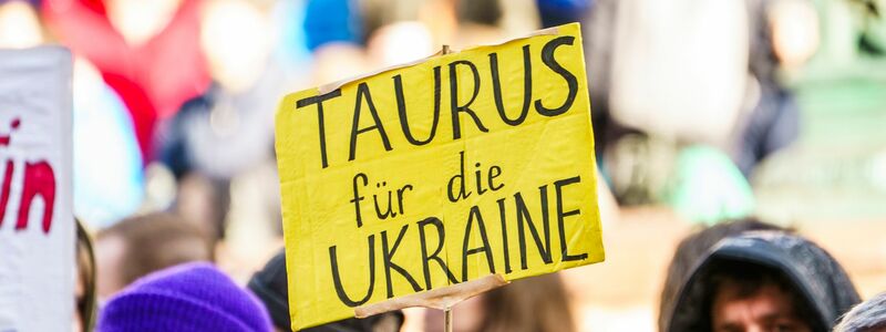 Bei einer Demonstration zum zweiten Jahrestag des russischen Angriffskrieges auf die Ukraine fordern Teilnehmer die Lieferung von Taurus-Marschflugkörper. - Foto: Andreas Arnold/dpa