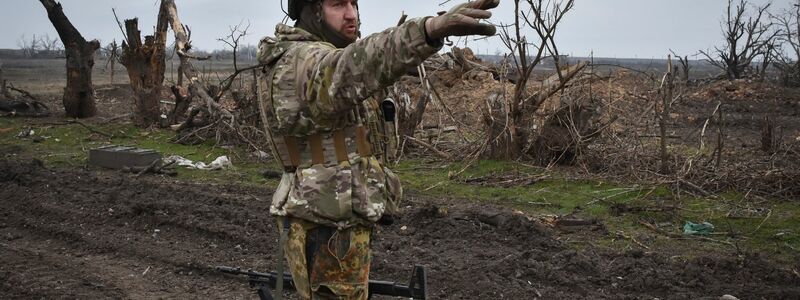 Ein ukrainischer Soldat zeigt auf die russische Stellung an der Frontlinie in dem Dorf Robotyne. - Foto: Andriy Andriyenko/AP/dpa