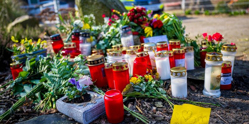 Blumen und Kerzen liegen vor einem Einfamilienhaus in Scheeßel. - Foto: Sina Schuldt/dpa