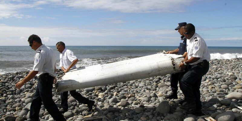Techniker tragen ein Wrackteil, die Flügelklappe eines Flugzeugs, über einen Strand bei Saint-André, Réunion. - Foto: Raymond Wae Tion/MAXPPP/QUOTIDIEN DE LA REUNION/dpa