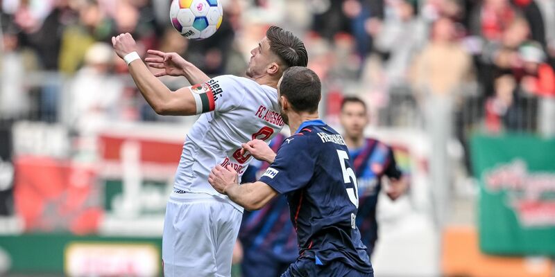 Der Augsburger Ermedin Demirovic (l) behauptet den Ball gegen Heidenheims Benedikt Gimber. - Foto: Harry Langer/dpa