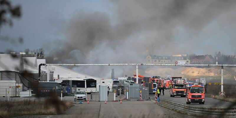 Feuerwehrmänner löschen die letzten Brandstellen in der Flüchtlingsunterkunft am ehemaligen Flughafen Tegel. - Foto: Sebastian Gollnow/dpa