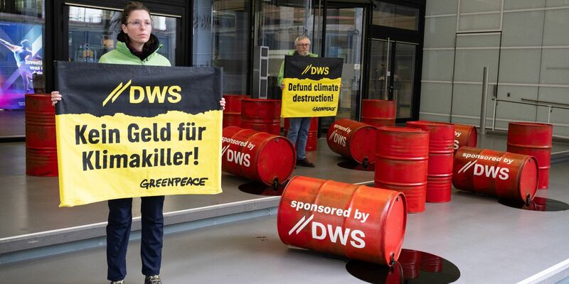 Mit roten Ölfässern protestieren Aktivisten von Greenpeace vor der Zentrale von DWS Investment in Frankfurt gegen die Investitionspolitik des Fonds. - Foto: Boris Roessler/dpa
