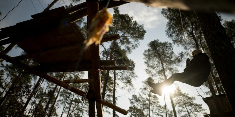 Eine Aktivistin seilt sich von einem Hochsitz ab. - Foto: Sebastian Christoph Gollnow/dpa