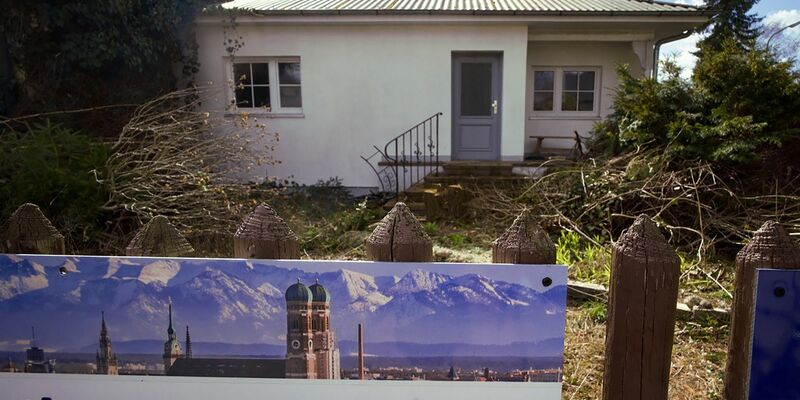 Ein zum Abriss bestimmtes Münchner Einfamilienhaus mitsamt dem Werbeplakat einer Immobiliengesellschaft. - Foto: Carsten Hoefer/dpa