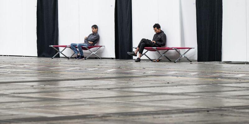 Geflüchtete sitzen auf Feldbetten in einer Massenunterkunft in Frankfurt: Viele Geflüchtete wünschen sich mehr Hilfe in Asyl- und Flüchtlingsfragen. - Foto: Boris Roessler/dpa