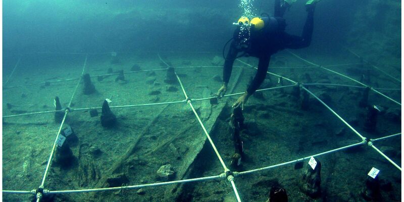 Ein Kanu wird Boden des Braccianosees ausgegraben. Die abgenutzten Überreste der mehr als 7000 Jahre alten Kanus lassen erahnen, wie ausgeprägt das Wissen über die Seefahrt bereits in der Jungsteinzeit war. - Foto: Gibaja Et Al/2024, Plos One, C/dpa