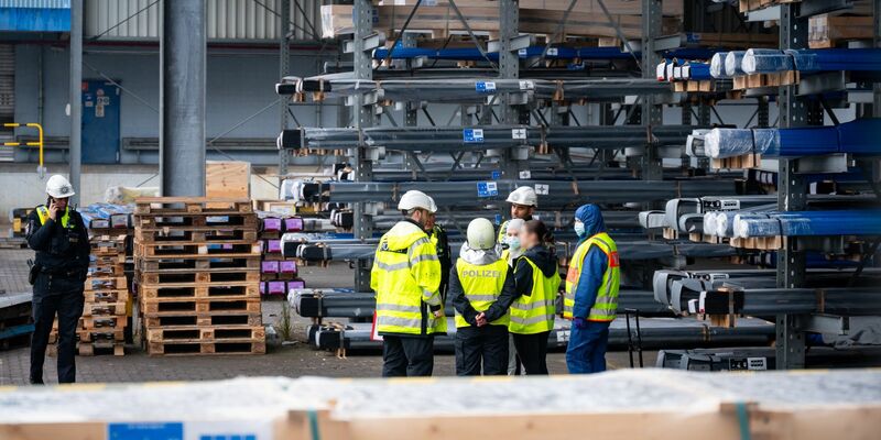 Ermittler und Polizisten stehen nahe der Unglücksstelle am Hamburger Hafen. - Foto: Jonas Walzberg/dpa