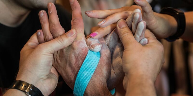 Die beiden Schiedsrichter binden bei den Deutschen Meisterschaften im Armwrestling die Hände der Athleten mit einem Gurt zusammen, um ein erneutes Abrutschen zu verhindern. - Foto: Andreas Arnold/dpa