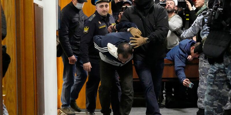Ein Tatverdächtiger wird von Polizisten und FSB-Beamten im Basmanny-Bezirksgericht eskortiert. - Foto: Alexander Zemlianichenko/AP