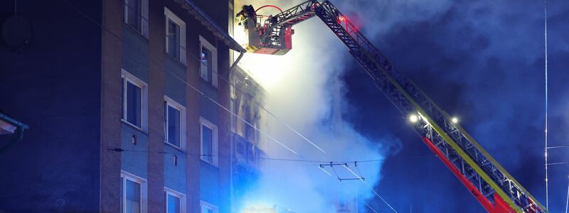Von einer Drehleiter aus bekämpft ein Feuerwehrmann den Brand in dem Mehrfamilienhaus. - Foto: Gianni Gattus/Blaulicht Solingen/dpa