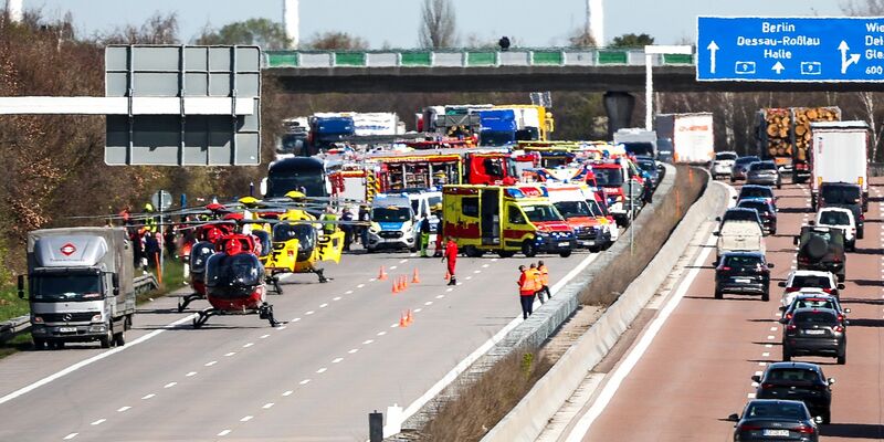 Ein Feuerwehrmann untersucht den Reisebus hinter mobilen Sichtschutzwänden. - Foto: Jan Woitas/dpa