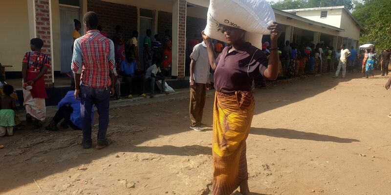 Eine Frau trägt einen Sack mit Maismehl, den sie in einem Verteilungszentrum des Welternährungsprogramms erhalten hat: Im südlichen Afrika wurde der Notstand ausgerufen. - Foto: Kenneth Jali/AP/dpa