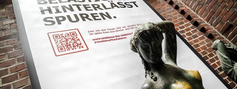 Plakat mit der Aufschrift «Sexuelle Belästigung hinterlässt Spuren» hinter der Bronzeskulptur «Jugend» von Bernhard Hoetger in Bremen. - Foto: Sina Schuldt/dpa