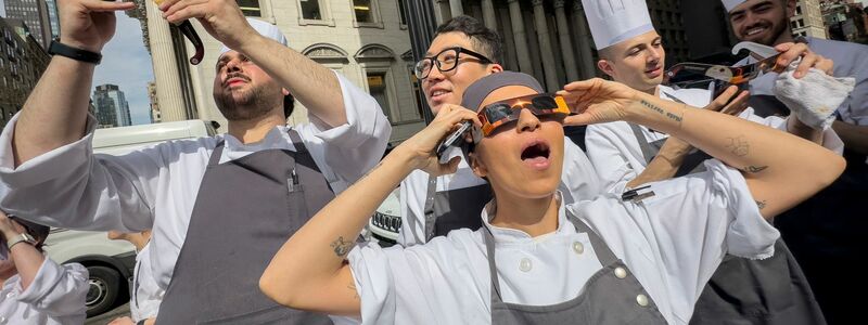 Angestellte eines Restaurants im Flatiron District von Manhattan machen eine Pause, um die Sonnenfinsternis zu betrachten. - Foto: John Minchillo/AP/dpa