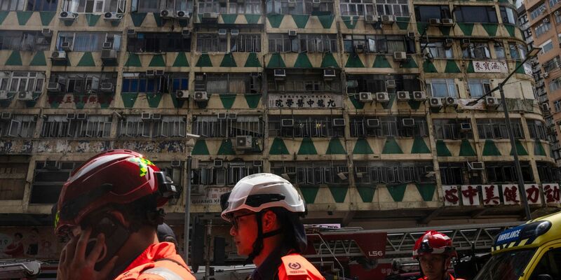 Im Hintergrund ist das ausgebrannte Hochhaus in Hongkong zu sehen - bei der Feuerwehr waren zahlreiche Hilferufe eingegangen. - Foto: Louise Delmotte/AP