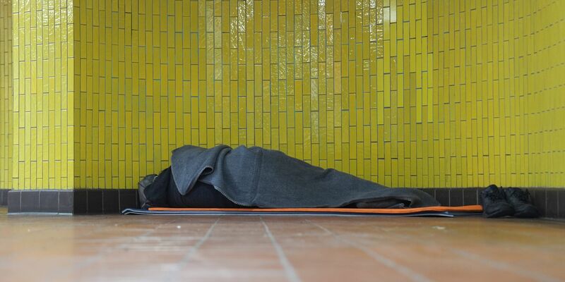 Ein Obdachloser liegt in seinem Schlafsack in einer U-Bahnstation in der Hamburger Innenstadt. 17,7 Millionen Menschen waren 2023 in Deutschland von Armut oder Ausgrenzung bedroht. - Foto: Marcus Brandt/dpa