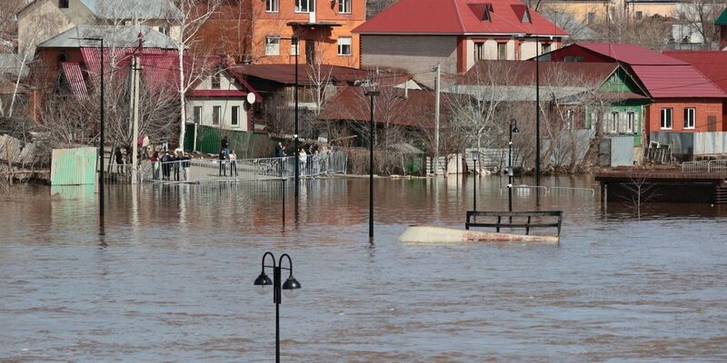 Anwohner stehen an einer Absperrung und beobachten ein überschwemmtes Gebiet im russischen Orenburg. - Foto: Uncredited/AP/dpa