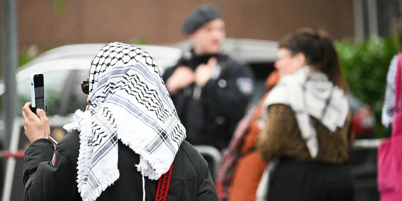 Teilnehmer des «Palästina-Kongresses» und Polizisten stehen vor der Veranstaltungshalle in Berlin-Tempelhof. - Foto: Sebastian Christoph Gollnow/dpa