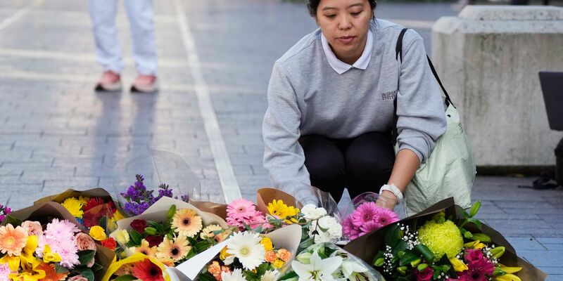 Eine Frau bringt Blumen zu einer improvisierten Gedenkstätte an der Bondi Junction. - Foto: Rick Rycroft/AP/dpa