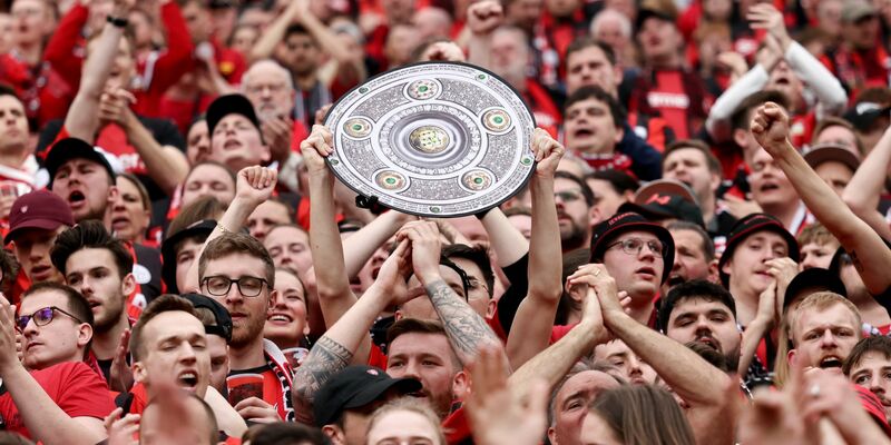 Fußball: Ein Leverkusener Fan hält während des Spiels eine Nachbildung der Meisterschale in den Händen. Bayer Leverkusen gewinnt die Deutsche Meisterschaft. - Foto: Rolf Vennenbernd/dpa